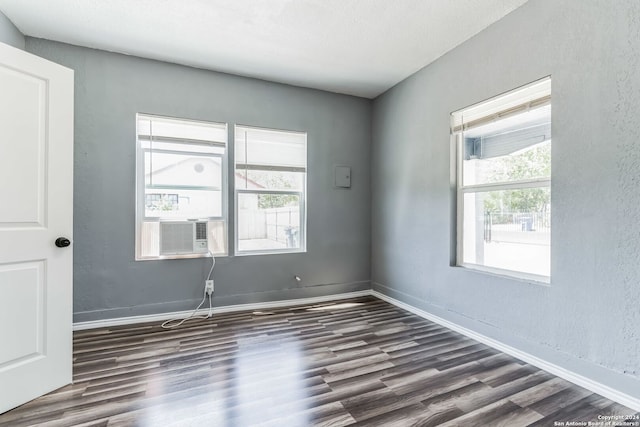 spare room with cooling unit, dark wood-type flooring, and a wealth of natural light