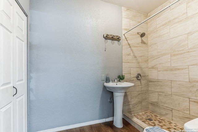 bathroom with toilet, sink, hardwood / wood-style floors, and tiled shower