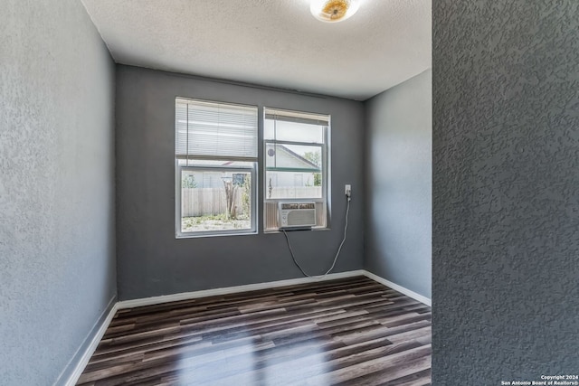 unfurnished room with cooling unit, dark wood-type flooring, and a textured ceiling