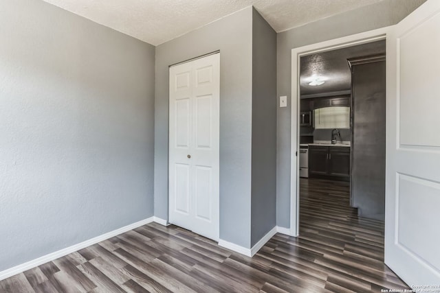 unfurnished bedroom featuring dark hardwood / wood-style flooring, a textured ceiling, and a closet