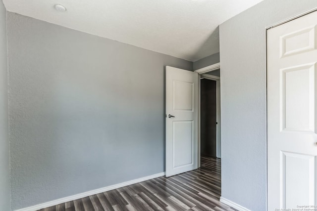 unfurnished bedroom with a textured ceiling and dark wood-type flooring