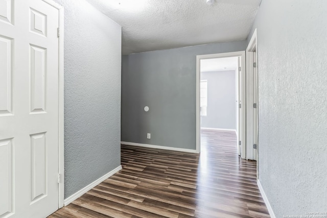 hallway with dark hardwood / wood-style flooring and a textured ceiling