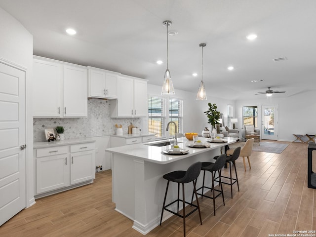 kitchen featuring white cabinets, sink, ceiling fan, and an island with sink