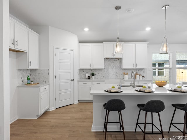 kitchen featuring decorative backsplash, sink, pendant lighting, light hardwood / wood-style flooring, and white cabinets