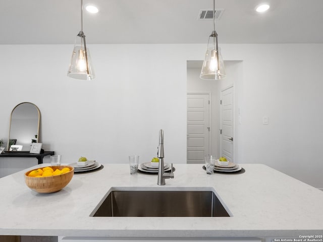 kitchen featuring light stone countertops, sink, a kitchen island, and hanging light fixtures