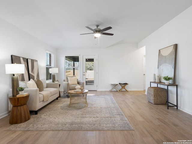 living room with ceiling fan, light hardwood / wood-style flooring, and vaulted ceiling