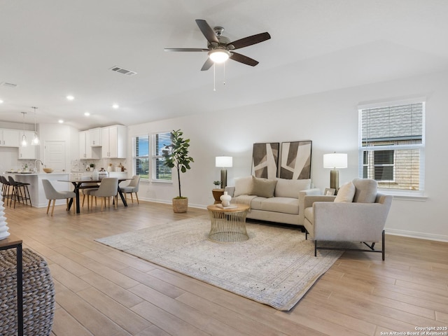 living room with ceiling fan and light hardwood / wood-style flooring