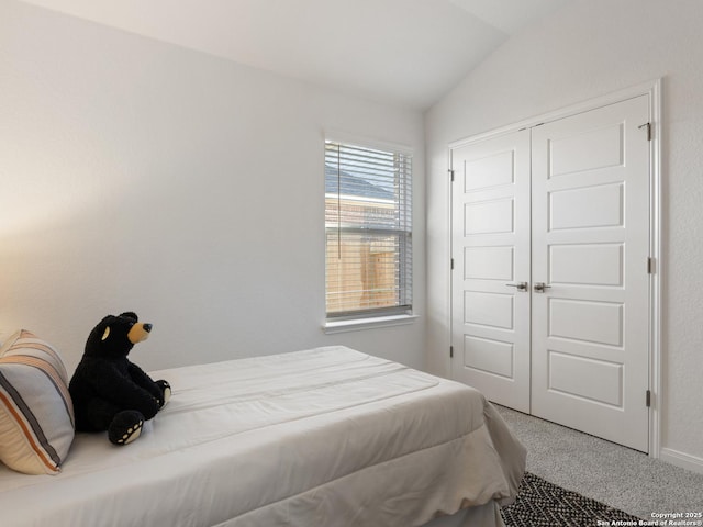 carpeted bedroom with vaulted ceiling and a closet