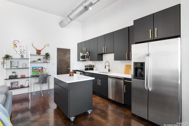 kitchen with a center island, sink, stainless steel appliances, and a high ceiling