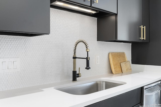 interior details featuring stainless steel dishwasher, decorative backsplash, and sink