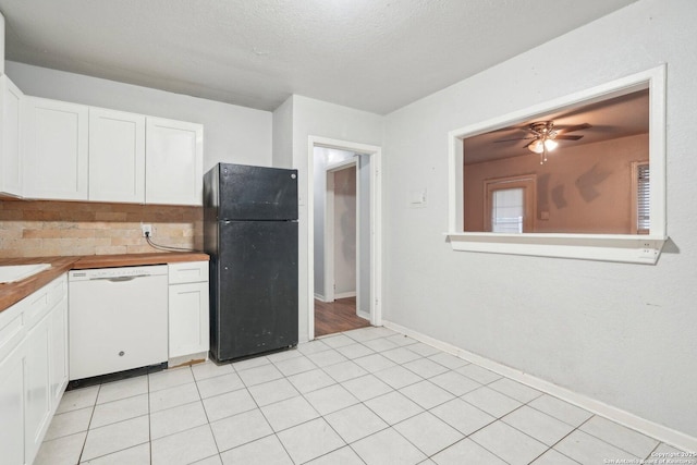 kitchen featuring decorative backsplash, black fridge, a textured ceiling, white dishwasher, and white cabinets