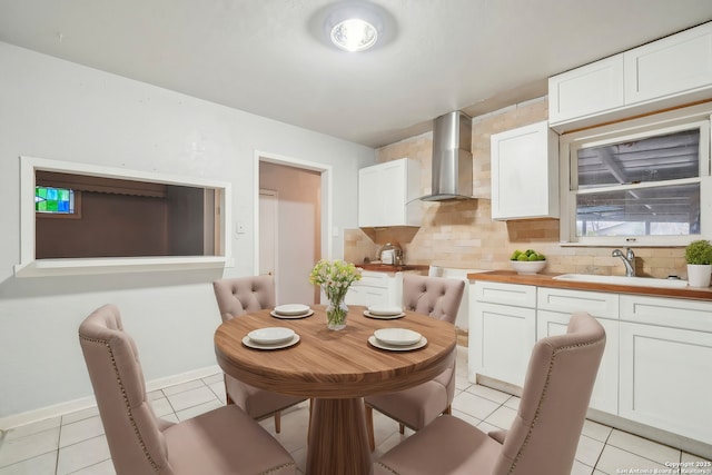 kitchen featuring white cabinets, light tile patterned floors, sink, and wall chimney range hood