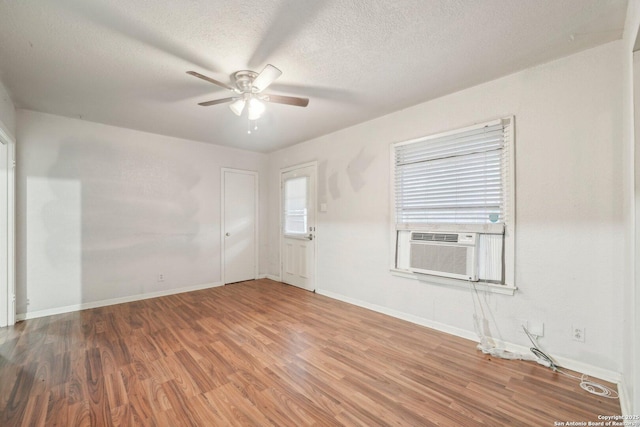 empty room featuring wood-type flooring, a textured ceiling, ceiling fan, and cooling unit