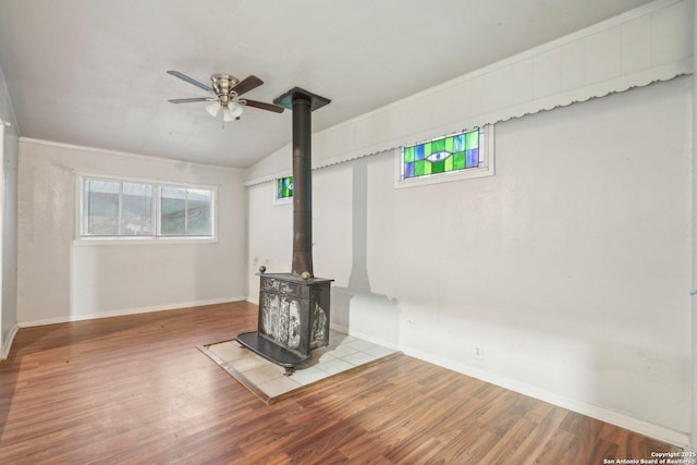 unfurnished living room featuring a wood stove, vaulted ceiling, light hardwood / wood-style flooring, and ceiling fan