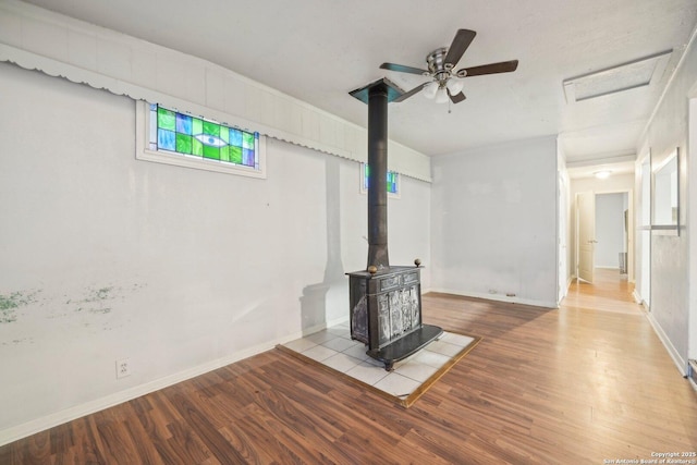 unfurnished living room with light hardwood / wood-style flooring, a wood stove, and ceiling fan