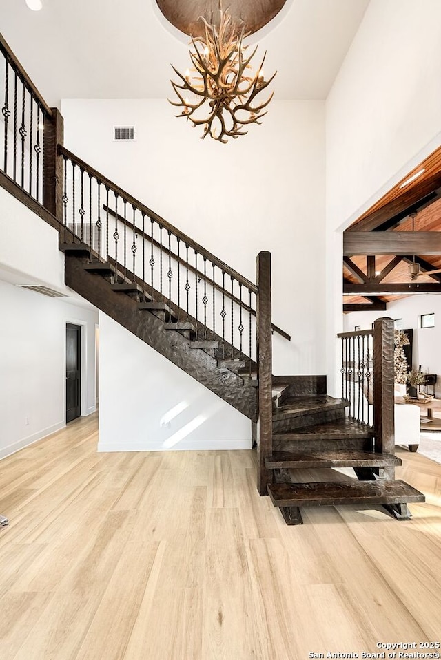 staircase with hardwood / wood-style floors and a notable chandelier