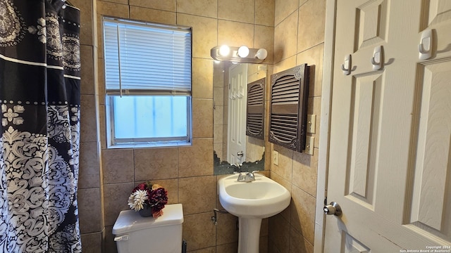 bathroom with radiator heating unit, tile walls, and toilet