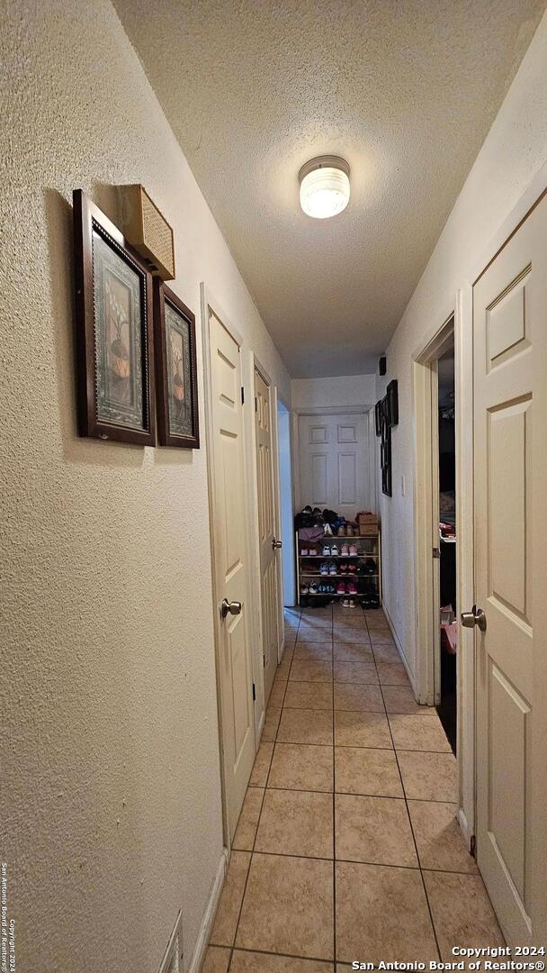 hallway with light tile patterned floors and a textured ceiling