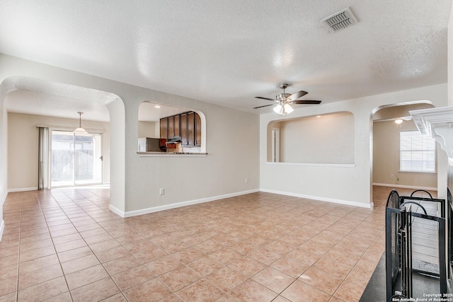 unfurnished living room with ceiling fan, light tile patterned flooring, and a textured ceiling