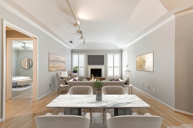 dining area with rail lighting, light hardwood / wood-style flooring, and crown molding