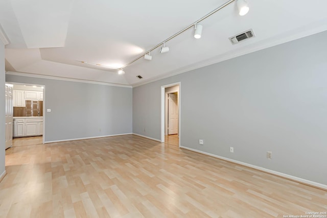 empty room with rail lighting, light hardwood / wood-style flooring, and crown molding