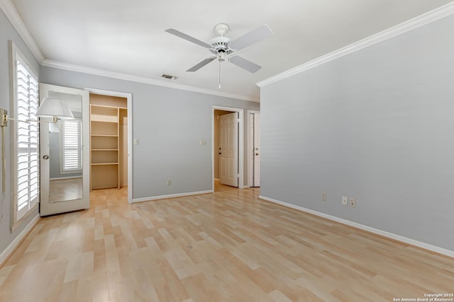 unfurnished bedroom with multiple windows, a closet, a spacious closet, and ceiling fan