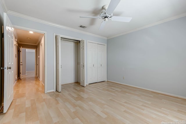 unfurnished bedroom featuring ceiling fan, light wood-type flooring, ornamental molding, and two closets