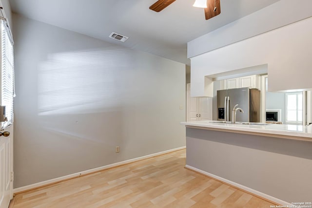 kitchen featuring white cabinets, sink, ceiling fan, stainless steel fridge, and light wood-type flooring