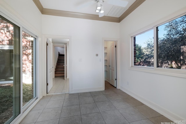 empty room with ceiling fan, light tile patterned flooring, a healthy amount of sunlight, and ornamental molding