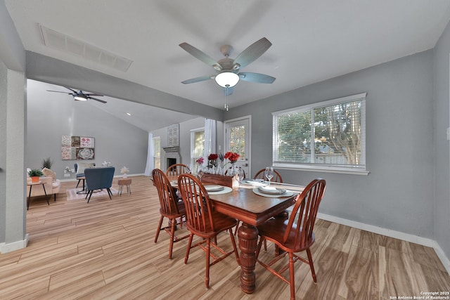 dining space featuring ceiling fan, lofted ceiling with beams, and a brick fireplace