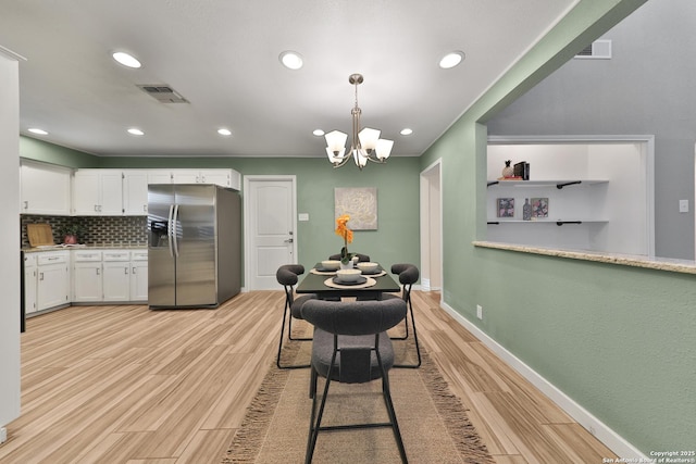 dining space with light hardwood / wood-style floors and an inviting chandelier