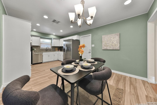 dining area featuring an inviting chandelier, sink, and light hardwood / wood-style flooring