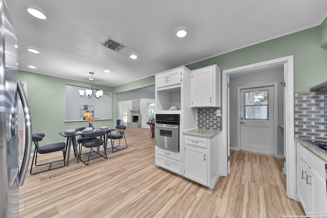 kitchen with decorative backsplash, pendant lighting, stainless steel appliances, and white cabinets