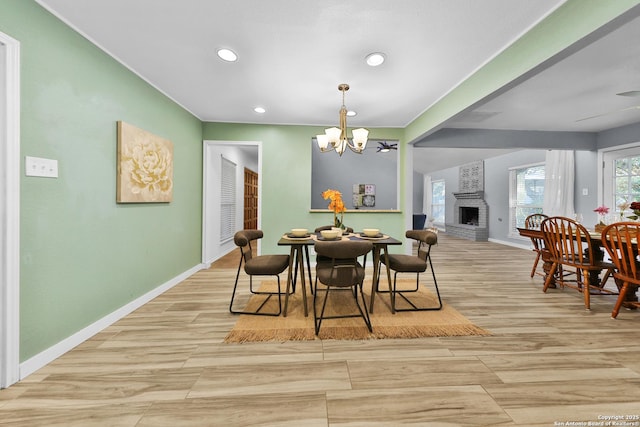 dining room with light hardwood / wood-style flooring, a fireplace, and a chandelier