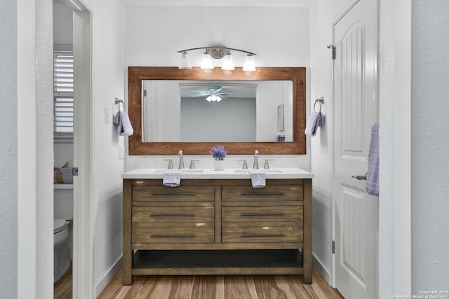 bathroom with hardwood / wood-style floors, vanity, toilet, and ceiling fan