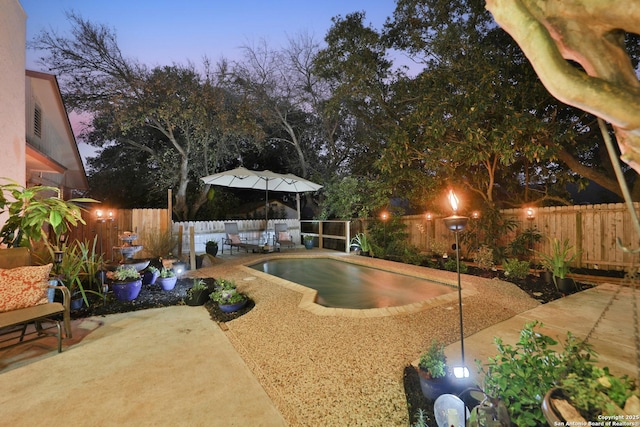 pool at dusk with a patio area