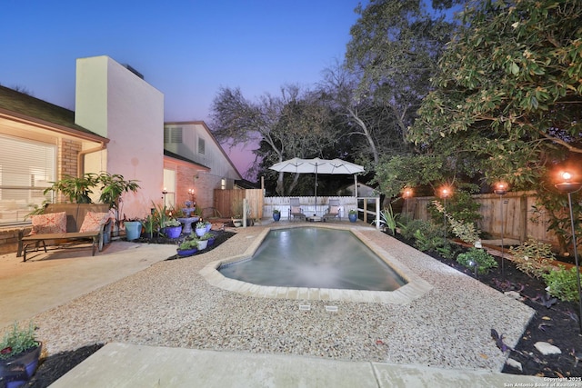 pool at dusk with a patio area