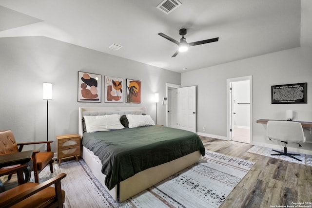 bedroom with ceiling fan, light hardwood / wood-style floors, vaulted ceiling, and ensuite bath