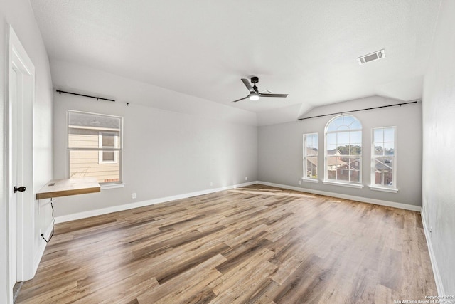 empty room with a healthy amount of sunlight, ceiling fan, light hardwood / wood-style flooring, and lofted ceiling