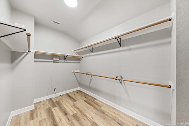 walk in closet with vaulted ceiling and light hardwood / wood-style flooring