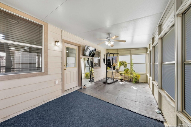 unfurnished sunroom featuring ceiling fan