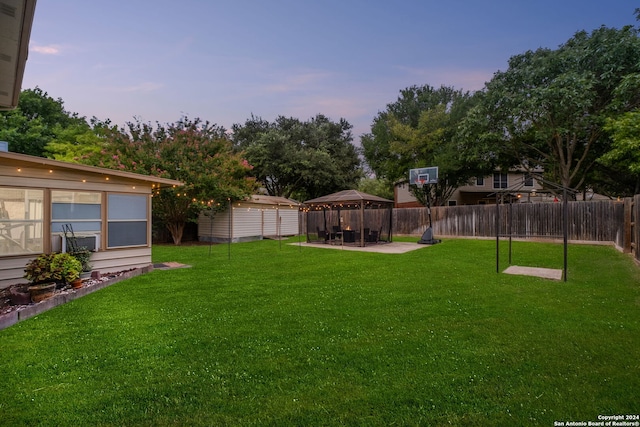 yard at dusk featuring a gazebo and a shed