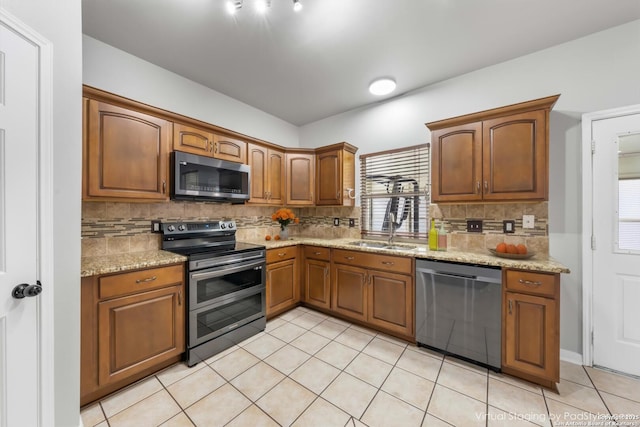 kitchen with sink, stainless steel appliances, decorative backsplash, and light stone countertops