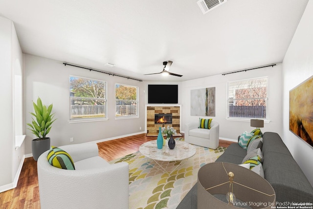 living room featuring wood-type flooring, a fireplace, ceiling fan, and a wealth of natural light