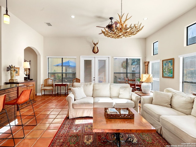 living room with a chandelier, light tile patterned floors, a high ceiling, and french doors