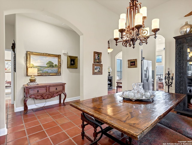 dining area with tile patterned flooring, a towering ceiling, and an inviting chandelier