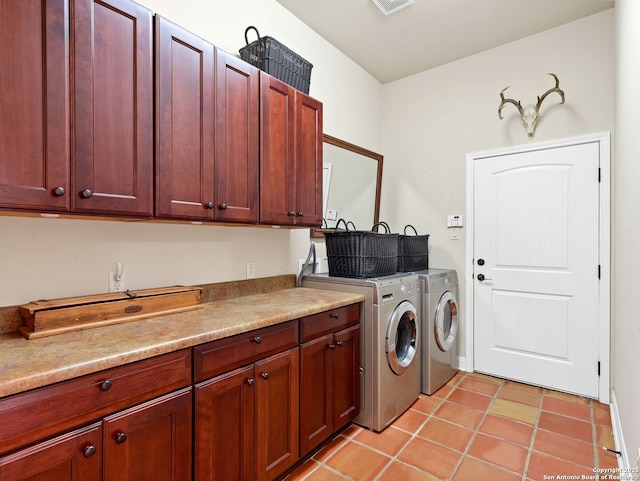 clothes washing area featuring cabinets, light tile patterned floors, and washing machine and clothes dryer