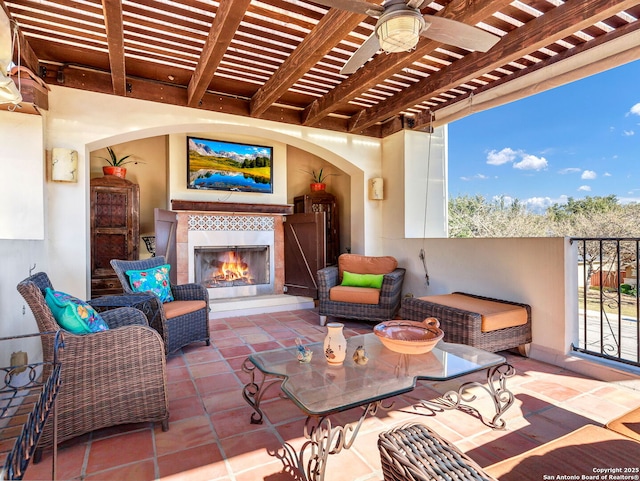 view of patio with ceiling fan, a pergola, and a tiled fireplace