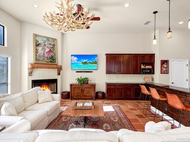 tiled living room with a tiled fireplace and a notable chandelier