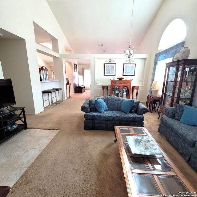 living room featuring carpet, high vaulted ceiling, and a chandelier